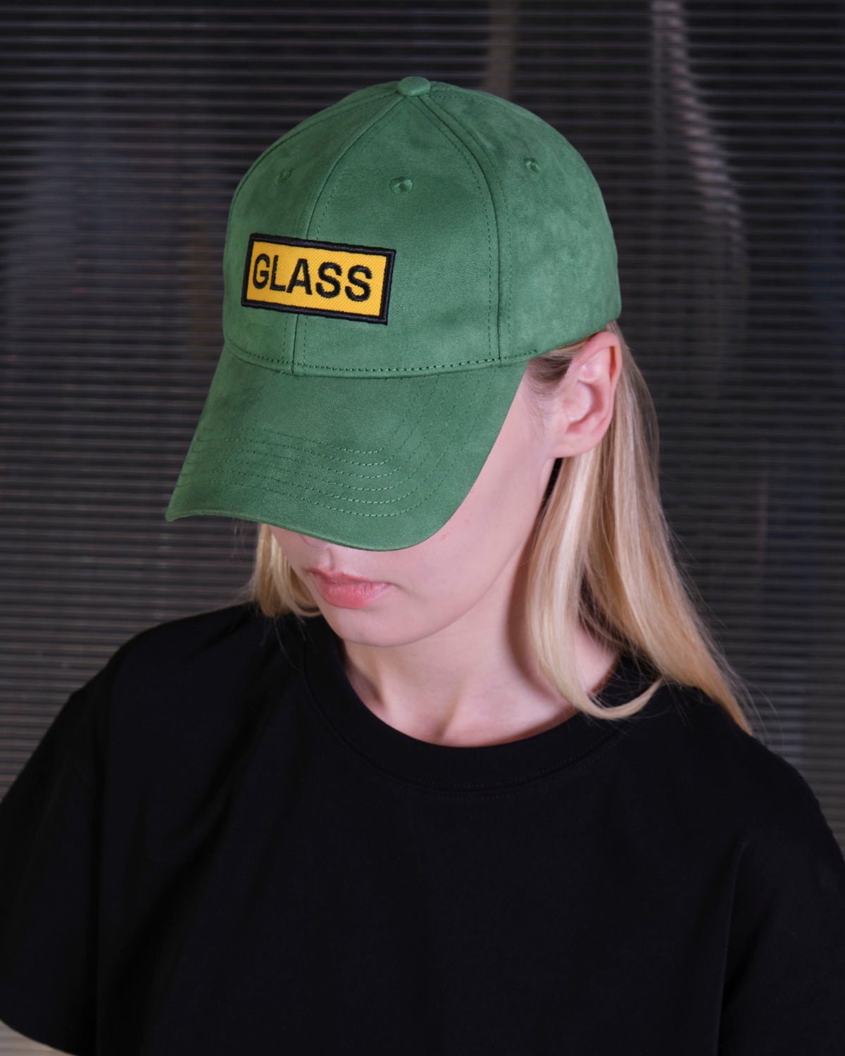 bABP Glass green eco-suede hat from the Signature Collection, lifestyle shot of a model in a black t-shirt, showcasing the yellow "GLASS" logo patch and premium texture