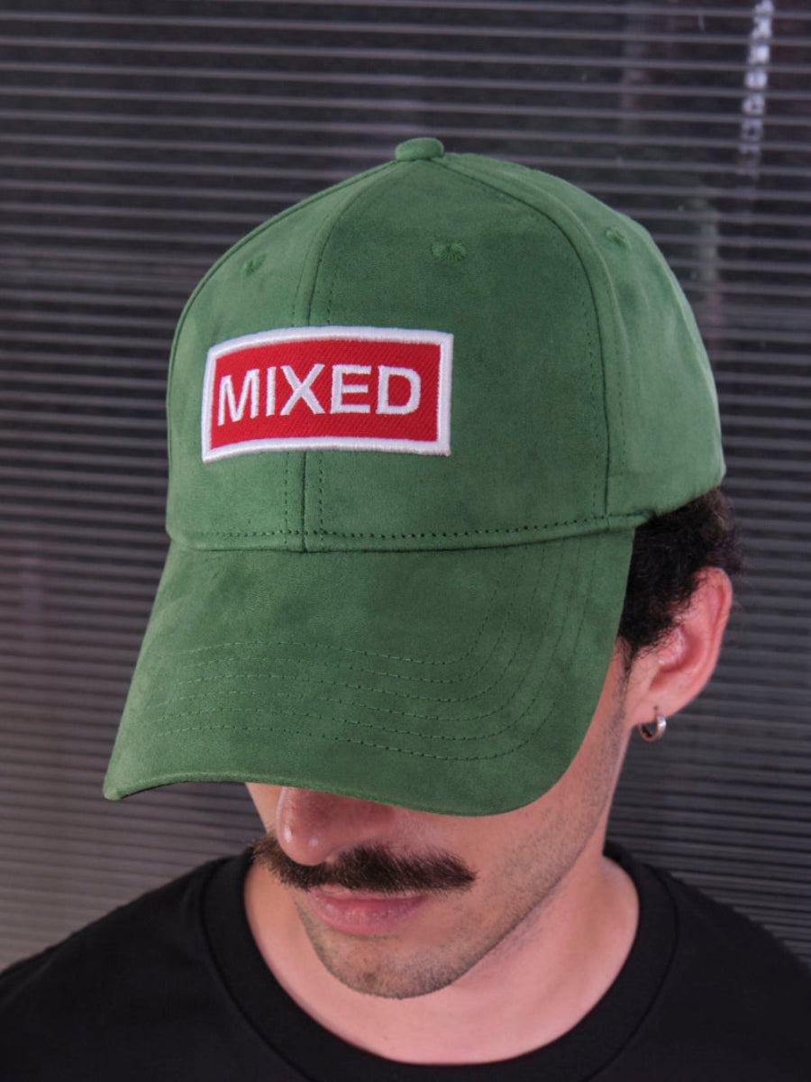 bABP Mixed green eco-suede hat from the Signature Collection, close-up portrait view of a model with a mustache wearing a black t-shirt, focusing on the red "MIXED" logo patch