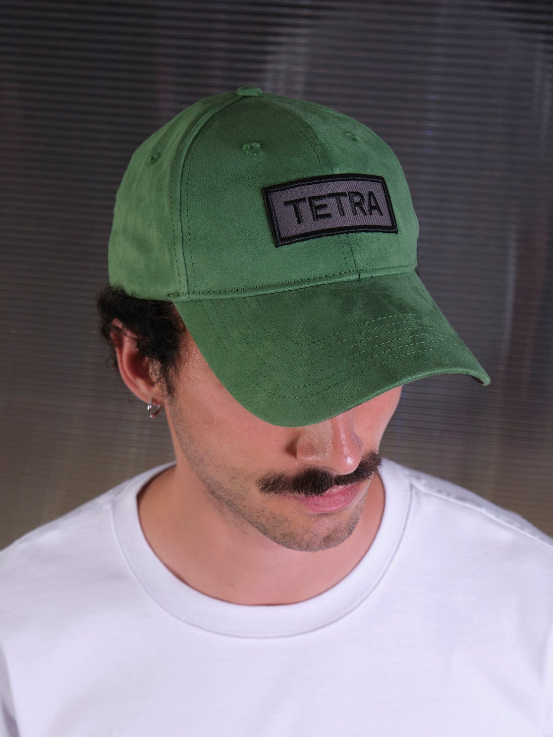 bABP Tetra green eco-suede hat from the Signature Collection, close-up portrait view of a model with a mustache, highlighting the black "TETRA" logo patch.