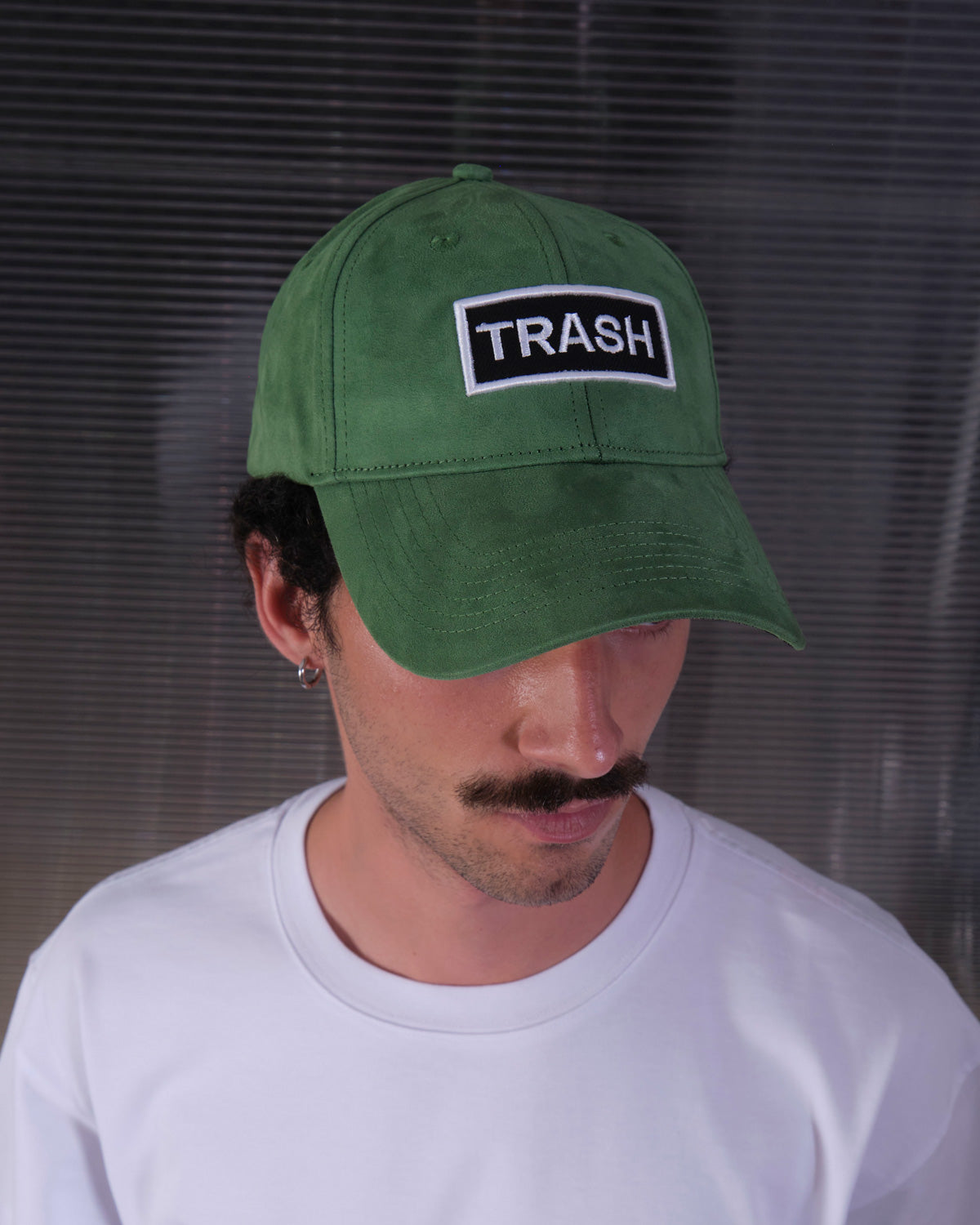 bABP Trash green eco-suede hat from the Signature Collection, portrait view on a model looking down, highlighting the white logo patch and premium texture