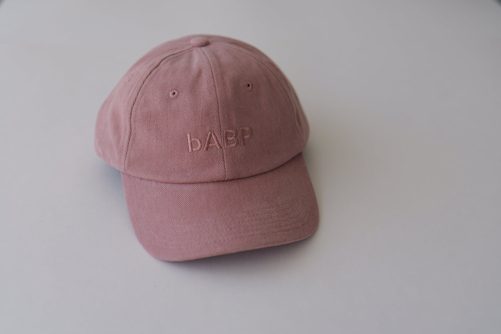Front view of bABP B-SIDE pink cotton dad hat with tonal logo embroidery, featured on a clean light gray background, premium streetwear style