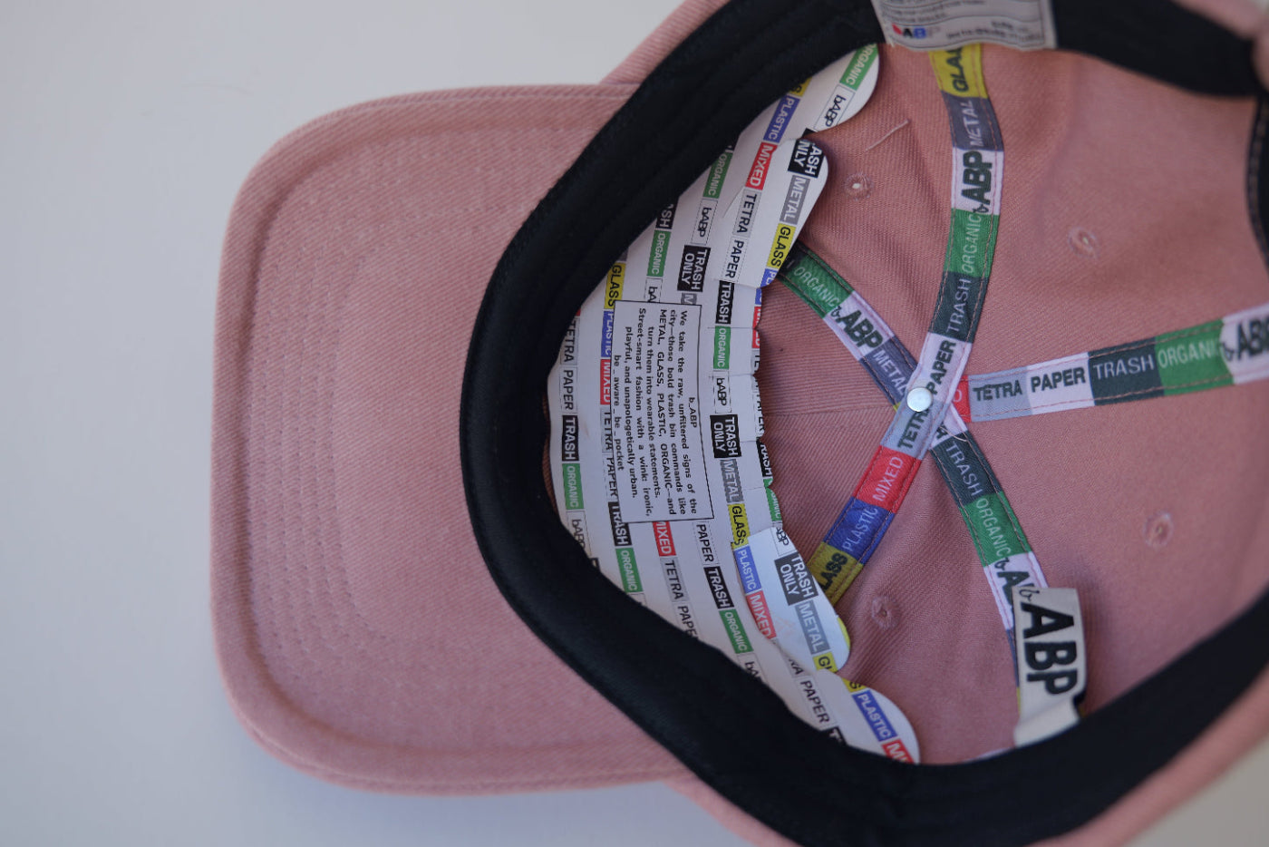 Interior view of the bABP B-SIDE pink heavy cotton hat showing the main bABP logo embroidery, branded "TRASH/METAL/PLASTIC" seam tapes, and secret "easter egg" label