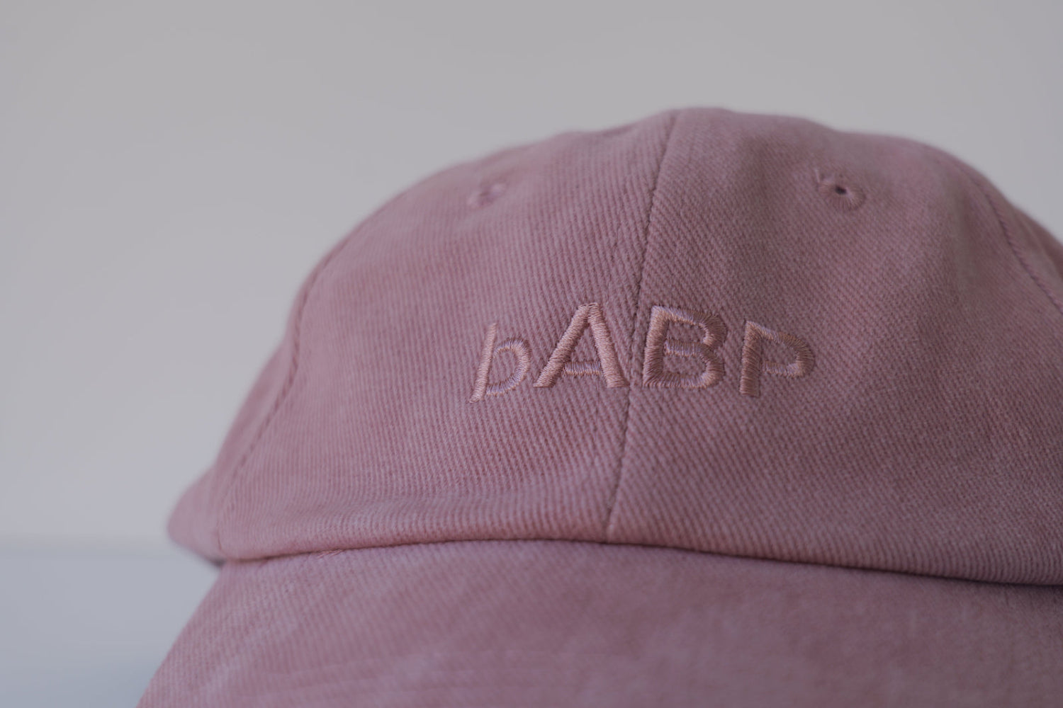 Extreme close-up of the bABP B-SIDE pink heavy cotton hat featuring tonal "bABP" logo embroidery on the front panel with visible fabric texture