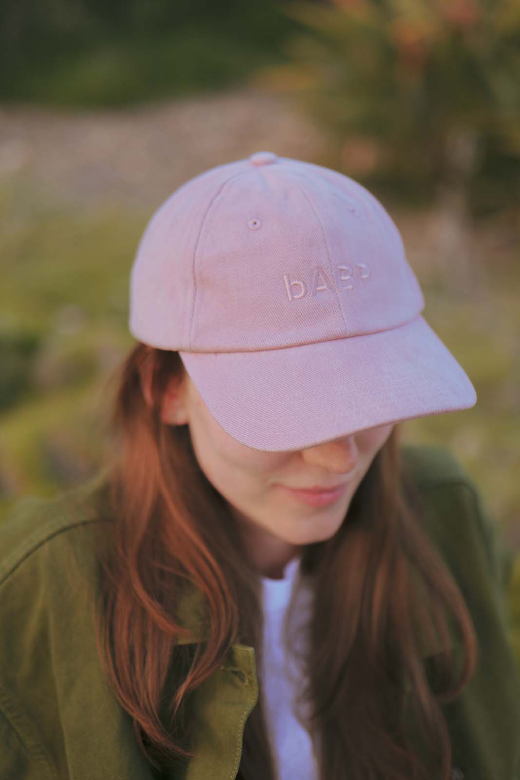 Close-up lifestyle portrait of a person wearing the bABP B-SIDE pink heavy cotton hat with tonal "bABP" embroidery, showcasing the "Street Approved Goods" series design