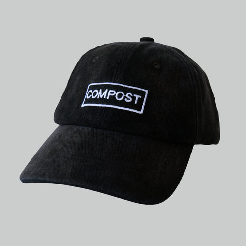 Professional studio shot of bABP B-SIDE: FRESH COMPOST black washed cotton hat with white logo embroidery, featured on a matching off-white grey background to highlight the tonal contrast