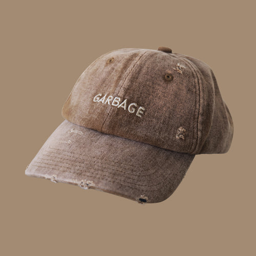 Professional studio shot of bABP B-SIDE: FRESH COMPOST "GARBAGE" tan distressed cotton hat with tonal embroidery, featured on a matching monochromatic sand-brown background