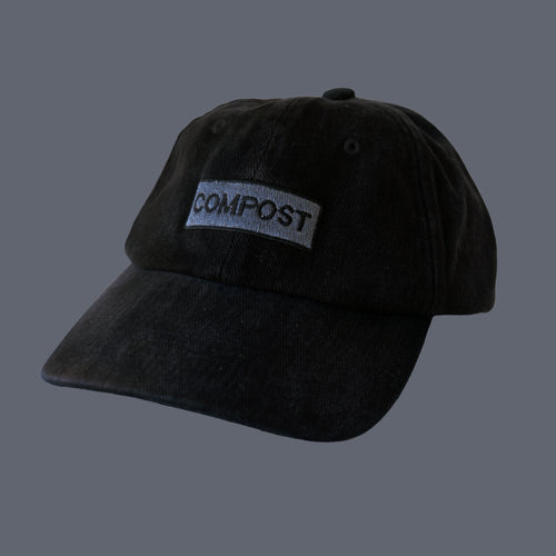 Front view of bABP "COMPOST" black washed cotton hat with grey logo embroidery, B-SIDE collection, on a solid grey background