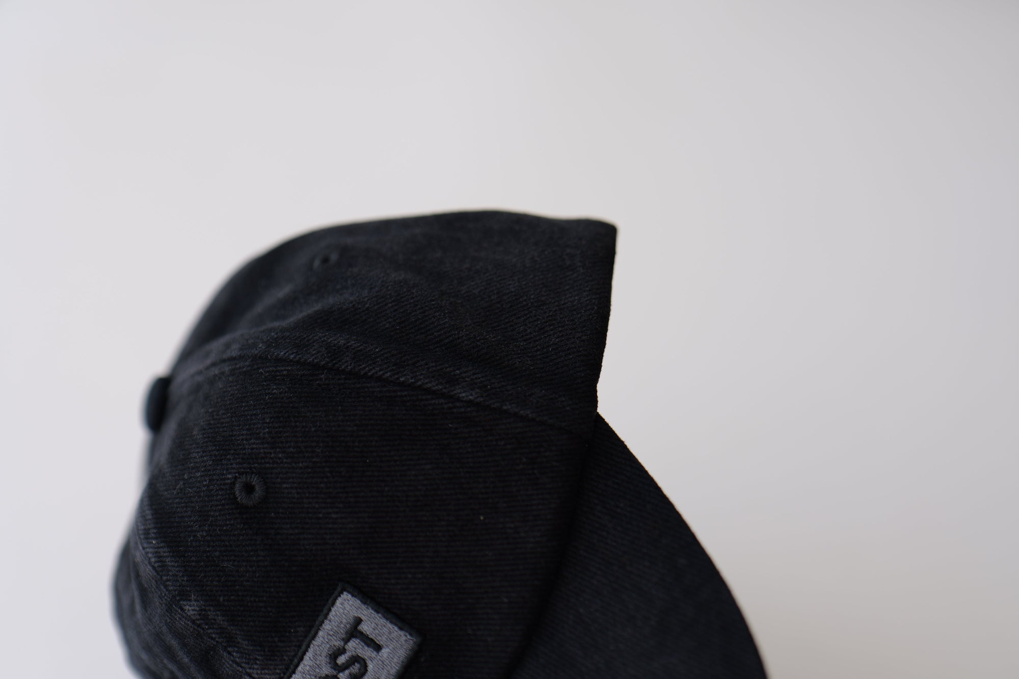Close-up side view of bABP "COMPOST" black washed cotton hat featuring a grey embroidered logo patch and premium distressed fabric texture, B-SIDE collection