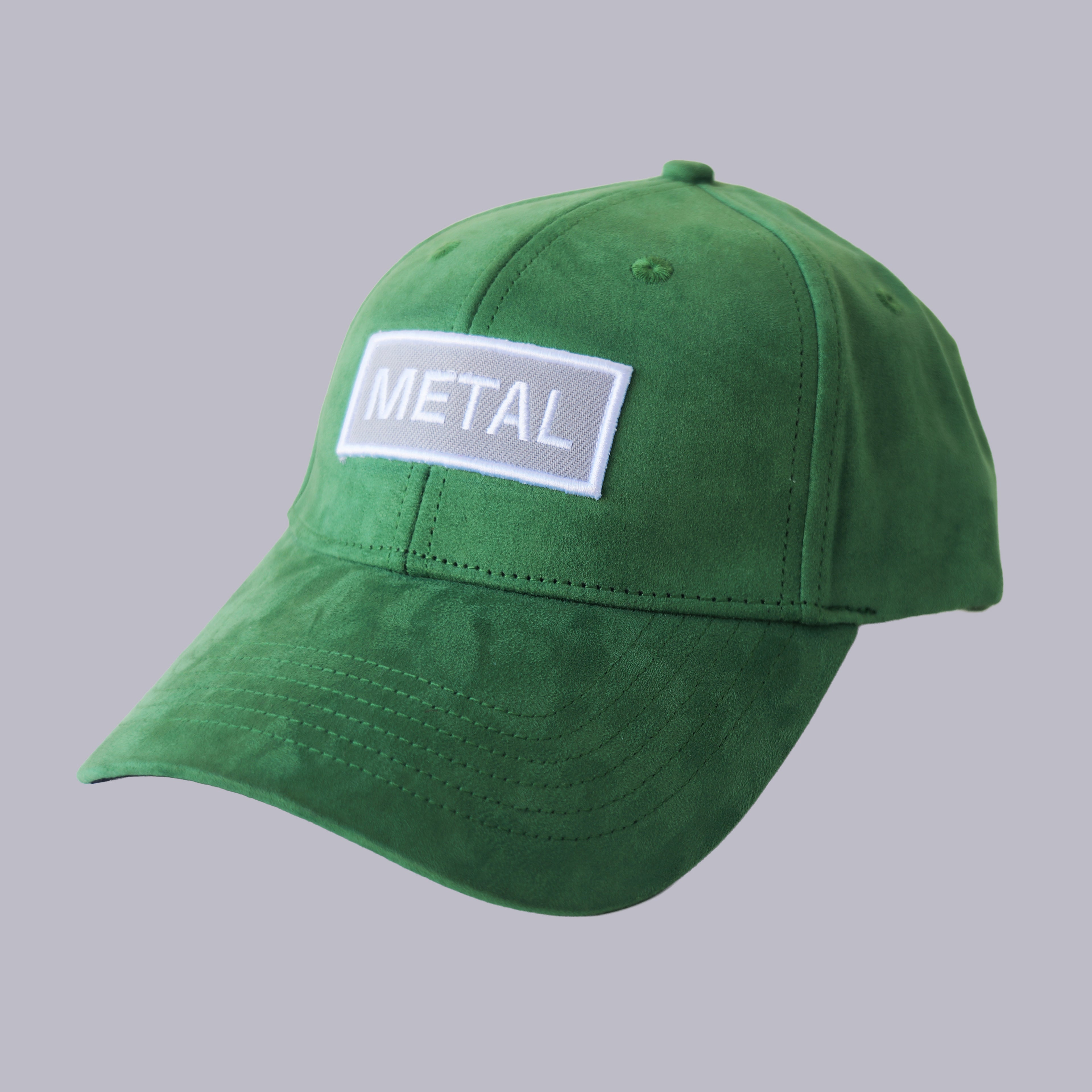 Professional studio shot of bABP "METAL" green eco-suede hat with a white and grey embroidered logo patch, featured on a matching monochromatic grey background