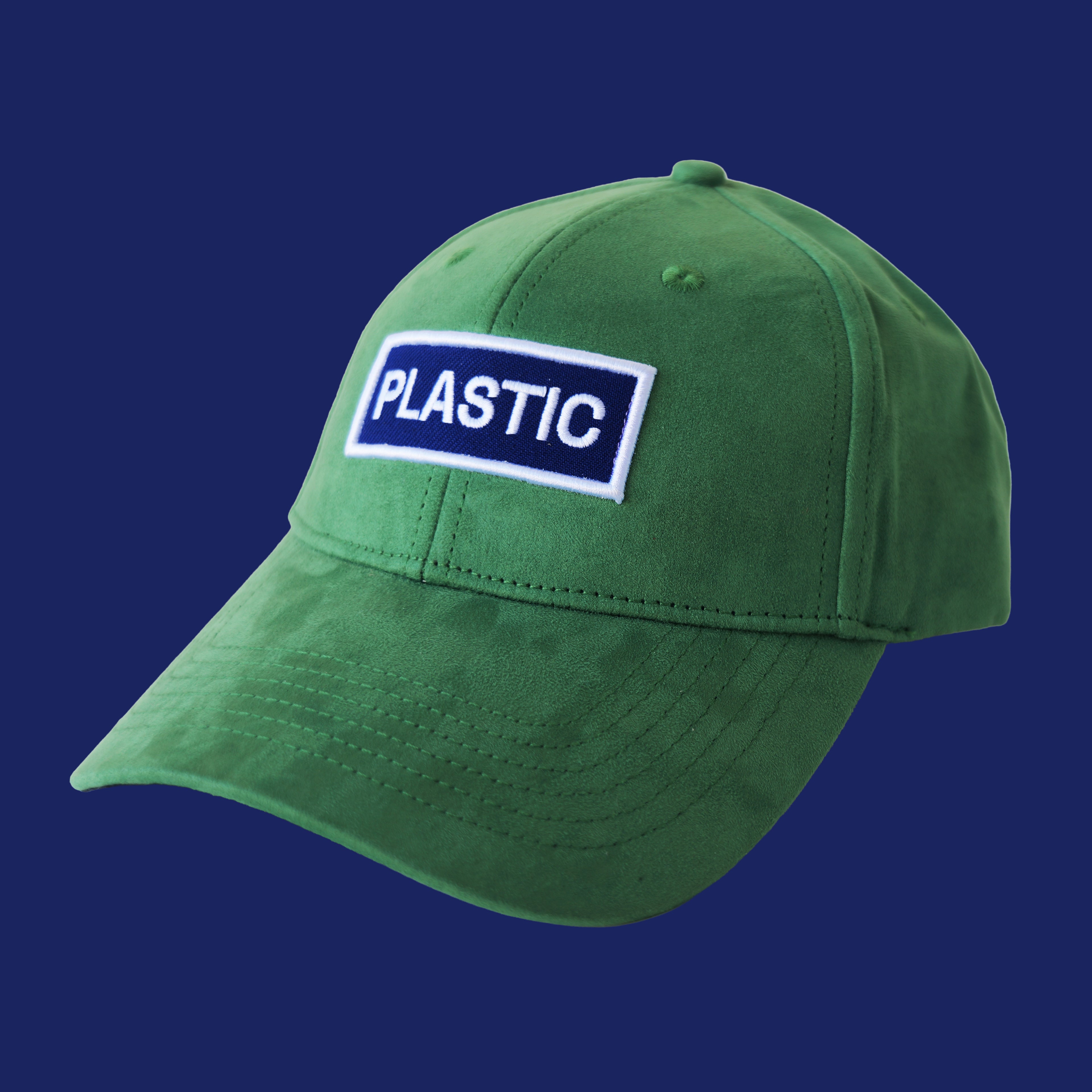 Professional studio shot of bABP "PLASTIC" green eco-suede hat with a white and blue embroidered logo patch, featured on a matching monochromatic dark blue background