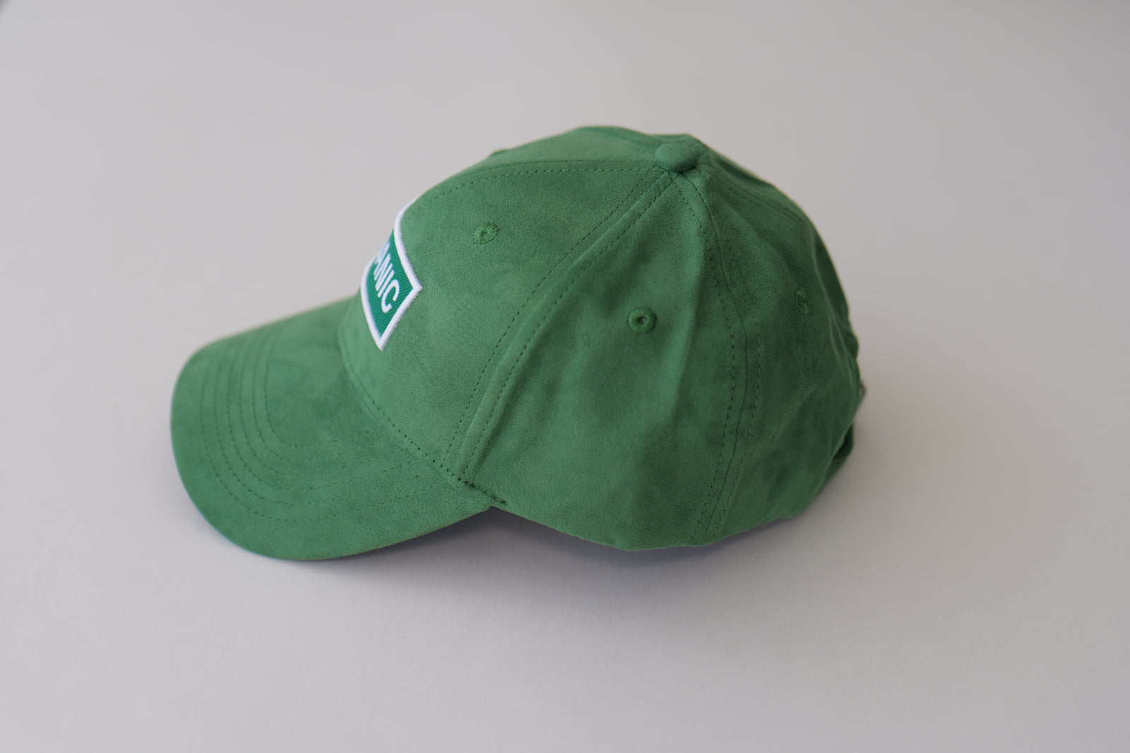 Side view of the bABP Signature Collection green eco-suede hat with the "ORGANIC" patch, showing the premium texture and structured crown