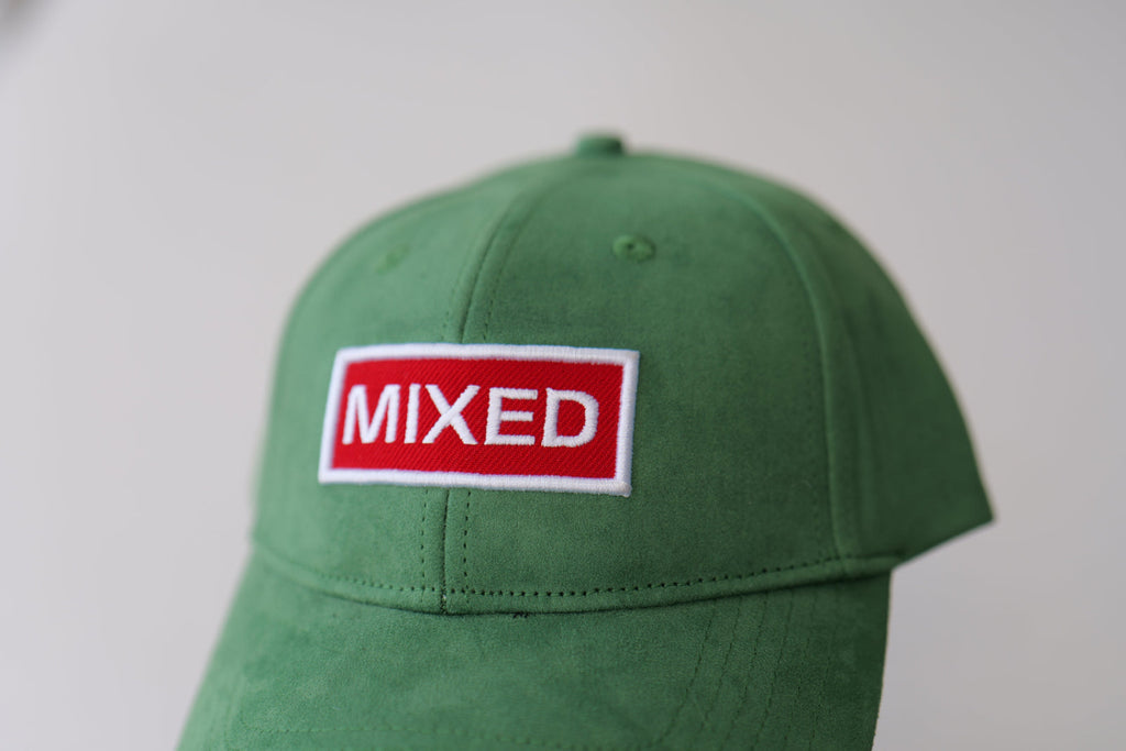 Top-down studio view of the bABP Signature Collection green eco-suede hat with a "MIXED" patch, showing the six-panel construction and premium fabric texture