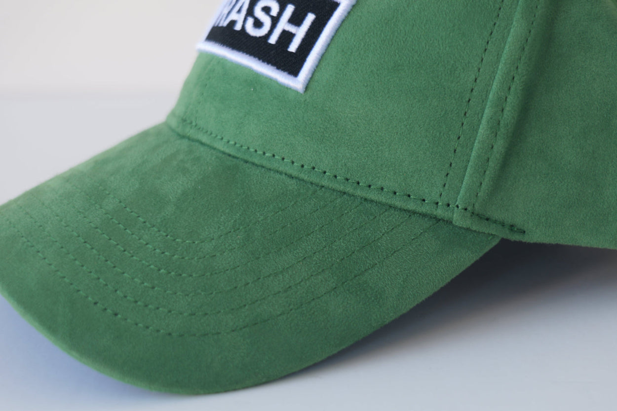 Extreme close-up side view of the bABP Signature Collection green eco-suede hat featuring a "TRASH" embroidered patch and premium fabric texture